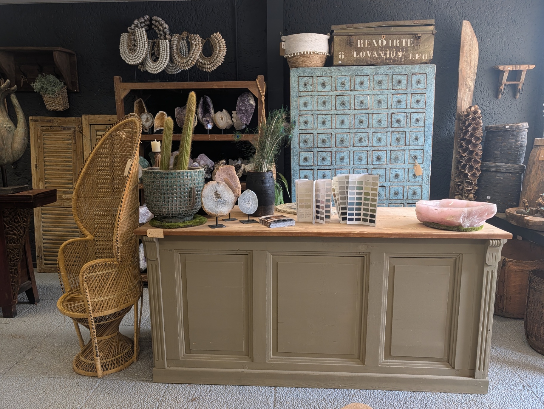 Olivgrüne Theke mit Farbmustern, Amethysten, Geoden und Rosenquarz-Schale im ländlichen Showroom in Goirle