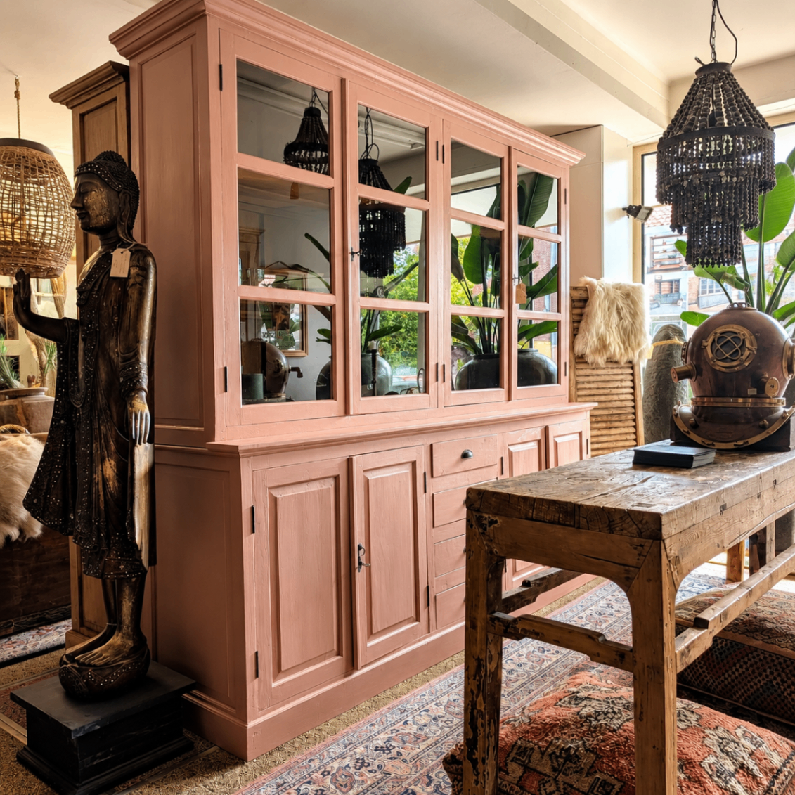 Altrosa Buffetschrank mit Glastüren, stehender Buddha und marokkanischer Teppich im Showroom in Goirle